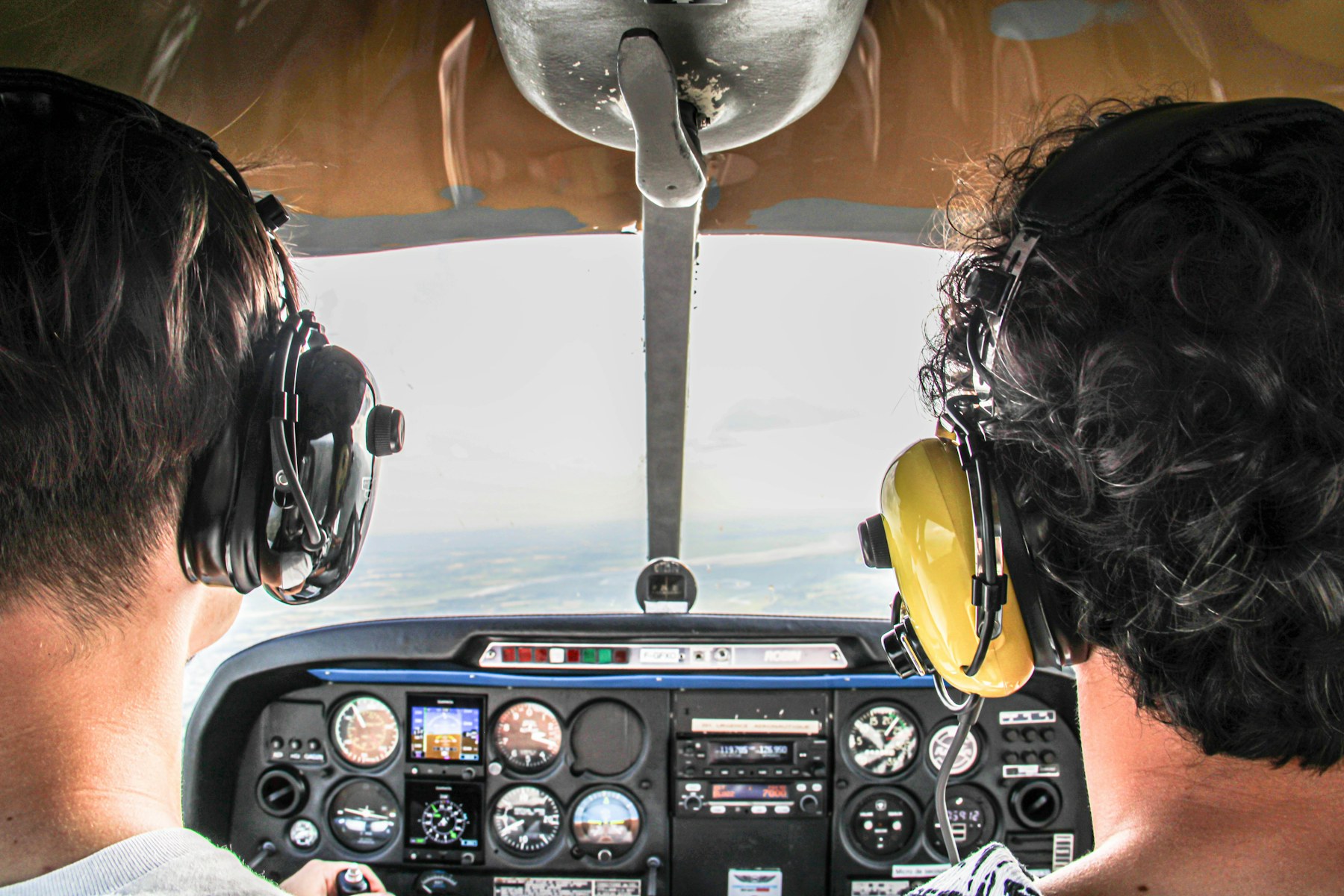 A student and instructor wearing headsets in a small airplane cockpit
